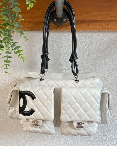 Vintage Chanel Cambon Reporter Bag🍒 Authentic. 8992860. White and black with silver accents. Quilted leather. Chanel logo on front. Two black handles. One exterior pouch, four exterior turn-lock closure pockets. Zip closure. Pink CC signature interior. One interior zipper pocket, two pouches, two pen holder pockets. Five metal feet. Circa 2004/2005. Some wear and markings, see photos. Made in France. Good condition. Pink Cc, Clothing Exchange, Chanel Cambon, 2010s Fashion, Dream Bag, Black Handles, Chanel Logo, Winter Fits, Black Handle