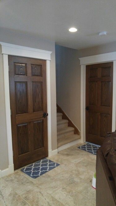 Our completed basement! Dark stained doors with white trim. Wall Trim And Door Colors, Dark Stained Doors With White Trim, Dark Wood Doors With White Trim, White Trim With Stained Doors, Brown Doors White Trim, Stained Doors With White Trim, Oak Doors With White Trim, Dark Stained Doors, Dark Doors With White Trim