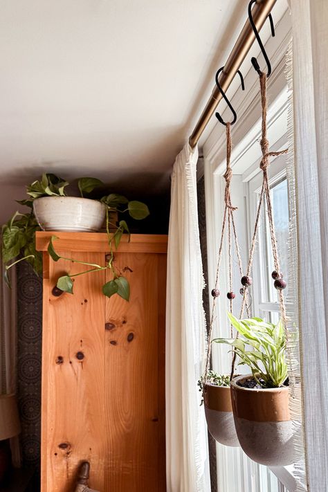 One of the easiest ways to update your bedroom decor is to add bedroom plants. Don't underestimate the power of plants!  Hanging plants from curtain rods is a fun way to add a touch of greenery and update your bedroom decor. Two of my favorite hanging plant varieties include pothos or string of pearls for a unique look. Check out our blog for more tips on updating your bedroom decor with plants. Your oasis awaits! Hanging Plant In Living Room, Plants Hanging From Curtain Rod, Hanging Plants Over Window, Hanging Plant Indoor Ideas, Inside Hanging Plants Ideas, Hang Plants In Window, Indoor Plant Hanging Ideas Diy, Hanging Indoor Plant Ideas, Curtain Rod Plant Hanger