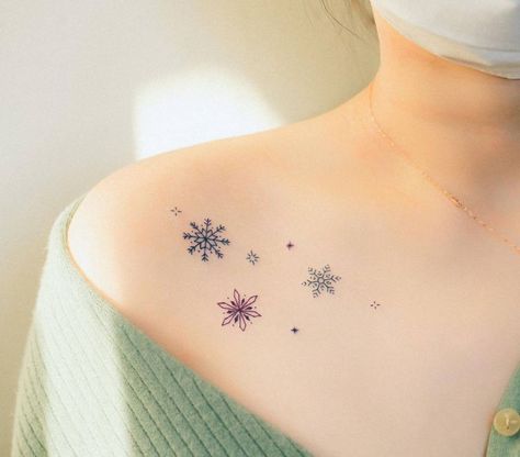 Colorful snowflakes tattooed on the collarbone Snowflake Tattoo Color, Snowflake Collarbone Tattoo, Woman Collarbone Tattoo, Snowflake Neck Tattoo, Snowflake Shoulder Tattoo, Snow Flake Tattoos For Women, Snowflake Chest Tattoo, Snowflake Hand Tattoo, Fine Line Snowflake Tattoo