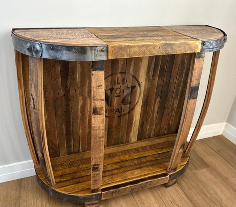 Rustic table created from whiskey barrel lids, staves, and tobacco lath make this table a unique combination to give you that one of a kind look. Table could be used as a entry, console table or small bar. Table top is a combination of reclaimed whiskey barrel tops and repurposed tobacco lath. Bottom shelf and solid back also consists of reclaimed tobacco lath. Each lath has its own color and texture due to the spearing and staining process in harvesting tobacco. Vertical supports are built using reclaimed whiskey staves. Steel rings that were once used in binding the whiskey barrels are polished and wrap both ends of the coffee table. Wood has been sanded and includes two coats of protective finish. Since every table is custom made from different whiskey barrels, size and color will vary Repurposed Whiskey Barrel, Wine Barrel Sink Bathroom, Barrel Sink Bathroom, Whiskey Table, Wine Barrel Sink, Small Bar Table, Bar Table Top, Barrel Sink, Entry Console