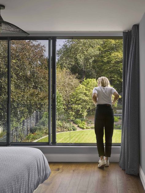 In this modern bedroom, a large sliding window can be opened, with a glass railing for safety. 1920s Home, 1920s House, Sunken Living Room, Sliding Window, Rear Extension, Glass Railing, Black Tiles, Large Dining Room, Bedroom Black