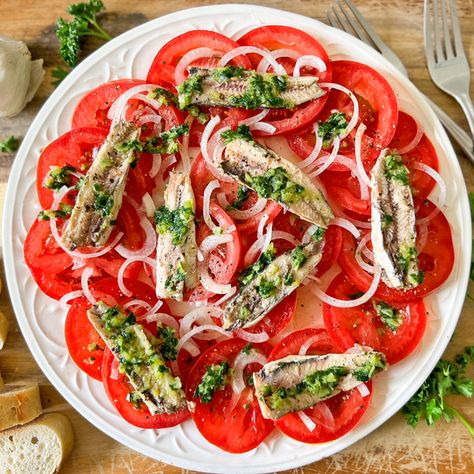 This Spanish Tomato & Sardine Salad, known as Ensalada de Tomate y Sardinas, is filled with Mediterranean flavors, made with simple ingredients and all done in just 10 minutes. Enjoy it as a tapas appetizer or even as a light dinner, next to a crunchy baguette and a bottle of Spanish wine. You can serve this salad either at room temperature or even chilled. Just cover with saran wrap and add into the fridge. It will hold for up to 3 to 4 days. Alternatively, you can make the dressing ahead of... Sardine Salad, Tapas Dishes, Seafood Stew, Lentil Stew, Fritter Recipes, Yogurt Recipes, Light Dinner, Tapenade, Healthy Ingredient