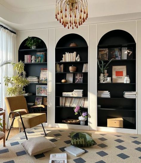 Picture of white arched bookcases with black backing and shelves, with amazing books and decor, a yellow chair and a rug for a reading nook Arch Top Bookcase, Corner Shelves Built In, Upstairs Reading Nook, Arched Bookcase Living Room, Arched Book Shelves, Two Tone Built Ins Bookshelves, Arched Library Wall, Arch Built In Shelves Fireplace, Arch Bookshelf Built Ins