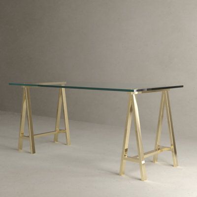 A modern and elegant glass top desk with saw horse-style legs. This desk is perfect for any space. Can be used as an office computer desk or as a dining table. Goes well in offices, home offices, and dining rooms. The clear glass top exposes the minimalistic saw horse leg design, turning this functional piece of furniture into an eye-popping conversation piece. It comes in two sizes and in two colors. The glass is 10 mm thick. Color (Frame): Gold, Size: 30" H x 71" W x 36" D | Everly Quinn Junui Parisian Home Office, Parisian Penthouse, Ceo Photoshoot, Glass Office Desk, Bohemian Office, Clear Desk, Saw Horse, Glass Top Desk, Glass Desk Office