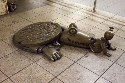 Cities 101: Uncovering NYC’s Sewer Alligator Legend, Fact or Fiction? - Shown: Tom Otterness-Life Underground-Alligator-Sewer-14th Street A-C-E- Subway-NYC - The NYC Department of Environmental Protection oversees the city’s massive sewer system, employing about 6,000 people. This small army is in charge of the nearly 7,400 miles of sewer pipe that flush a staggering 1.3 billion gallons of water every day. The department is quite friendly and responsive, as far as city services go. Fact Or Fiction, Manhattan Island, Sewer System, Places In New York, New Amsterdam, Bronze Sculpture, Environmental Protection, Funny People, Alligator