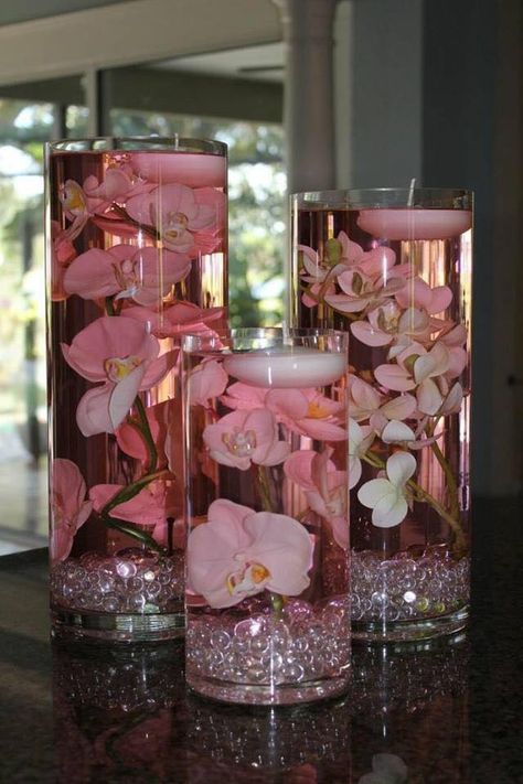 glass pillars, pink orchids, and floating tea candles. Floating Candle Centerpieces Diy, Store Ornaments, Floating Centerpieces, Diy Floating Candles, Unique Wedding Centerpieces, Diy Wedding Planner, Wedding Vase Centerpieces, Crafts Simple, Snowman Crafts Diy