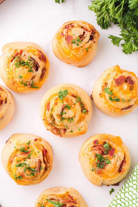 a couple of Cheddar Bacon Pinwheels on a white table Cheddar Bacon Ranch Pinwheels, Bacon Cheddar Ranch Pinwheels, Bacon Cheese Puffs, Bacon Pinwheels, Ranch Pinwheels, Bacon Puffs, Puff Pastry Pinwheels, Cream Cheese Pinwheels, Cheese Pinwheels