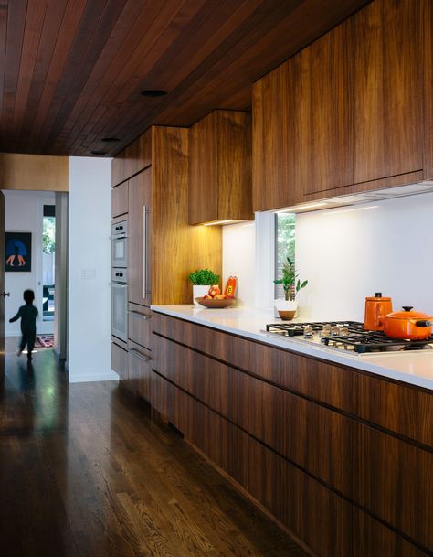 In the kitchen, interior designer Emily Knudsen Leland replaced purple laminate cabinets with flat-sawn eastern walnut, and added PentalQuartz countertops in polished Super White for contrast. The cooktop and oven are from Miele. Walnut Kitchen Cabinets, Modern Kitchen Renovation, Wooden Kitchen Cabinets, Walnut Kitchen, Mid Century Modern Kitchen, New Kitchen Cabinets, Kitchen Cabinets Makeover, Wood Kitchen Cabinets, Mid Century Kitchen