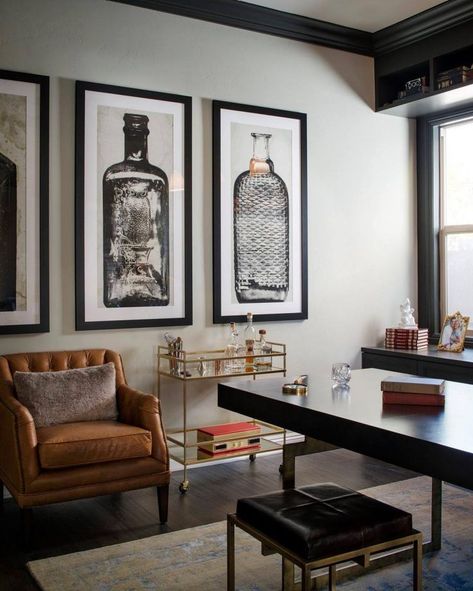 A glass-and-gold bar cart, brown leather armchair and oversized artwork of glass bottles give Mad Men-esque flair to this home office. Indigo Office, Home Office Masculine, Masculine Office Decor, Masculine Home Offices, Man Home Decor, Room Ideas Men, Bachelor Pad Decor, Room Decor For Men, Masculine Home Office