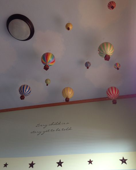 I wanted my daughter to have something fun to look up at in her bedroom. So I went beyond painting the ceiling blue and sponging on white puffy clouds. I hit Amazon and purchased a bunch of hot air balloons to hang from the ceiling. And she loves them!  For more, follow my board. http://www.pinterest.com/babauer20/around-the-bauer-house/ Ceiling Hanging Decor Nursery, Hot Air Balloon Ceiling Decor, Nursery Ceiling Ideas, Cloud Ceiling Playroom, Hot Air Balloon Hanging From Ceiling, Hot Air Balloon Room Decor, Blue Ceiling With Clouds, Sky Ceiling Mural Cloud, Balloon Ceiling