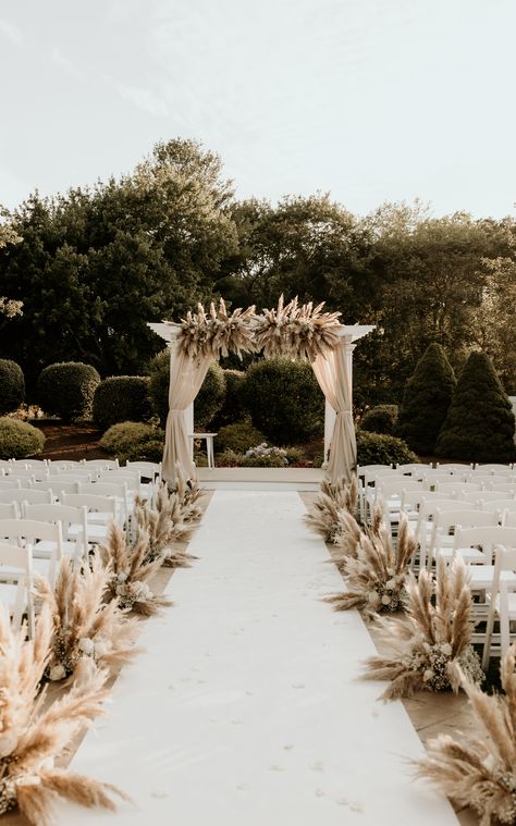 We're obsessed with this pampas grass wedding decor featuring arch draping, an aisle runner, and aisle decor. | Photography: Cami P Photography Pampas Grass Wedding Aisle Decor, Pampas Chair Decoration, Pampas Grass Wedding Ceremony Aisle, Pampas Down The Aisle, Wedding Ceremony Runner, Flowers Down The Aisle Wedding Outside, Wedding Arch Ideas Pampas, Pampas Grass Wedding Decor Isle, Outdoor Wedding Aisle Ideas Boho