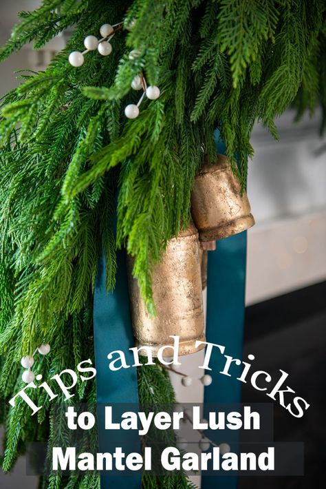 A fireplace mantel with faux Christmas garland on it in layers with antique tin bells and Teal green ribbons. Diy Mantle Garland, How To Attach Garland To Mantle, Garland On Mantle, Pine Garland Christmas, Diy Mantle, Holiday Mantle Decor, Mantle Garland, Holiday Mantle, Norfolk Pine