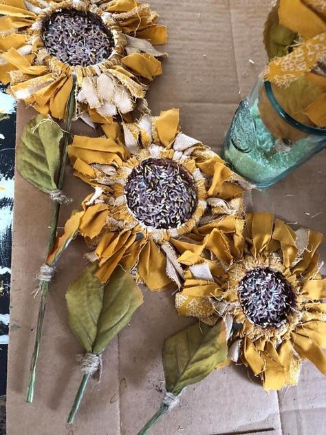 I made some canning jar lid, rag sunflowers. I used rice in the center and a variety of acrylics. Drilled a hole in the side of the lid and attached a wood dowel through it. Added leaves to the dowel with jute. Cloth Sunflowers Diy, Canning Jar Lid Flowers, Canning Jar Ring Rag Flowers, How To Make Rag Sunflowers, Rag Sunflowers, Rag Sunflower, Canning Lid Sunflower, Primitive Sunflowers Diy, Canning Jar Lid Sunflowers