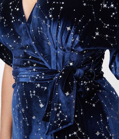 Wrap yourself in stars, dears! This sensational 1970s style wrap dress from Unique Vintage is crafted in a gorgeous navy blue velvet that dances with twinkling silver stars throughout. The sultry wrap design is secured with dual buttons creating a surplice neckline that is framed by dolman sleeves. The seamed high waist is cinched by a matching self tie sash while the skirt cascades to a sweeping midi silhouette!Available in sizes XS-5X while supplies last.