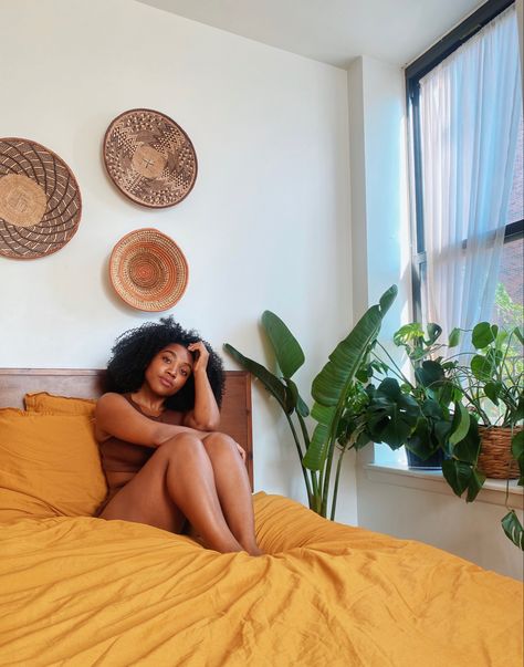 Boho room decor with mustard bedsheets, East African wall basket art, and plants. Afro Boho Office Decor, African Boho Aesthetic, Afro Centric Boho Bedroom, Afro Boho Apartment, African Boho Bedroom, Afro Bohemian Style Decor Bedroom, Afro Boho Bedroom, Mustard Boho Bedding, Afro Boho Decor