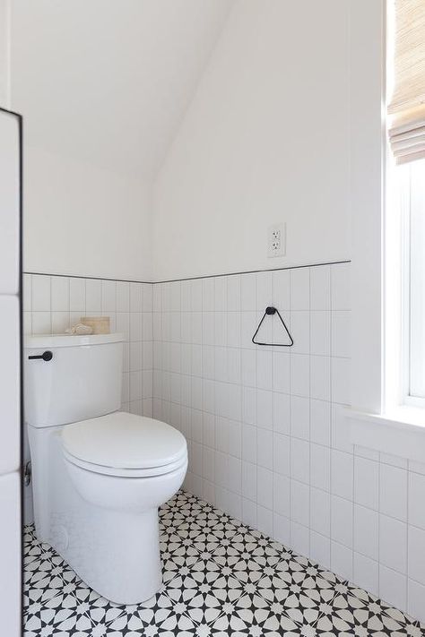 Half tiled vertical walls with black trim in a black and white bathroom boasting cement floor tiles under a vaulted ceiling. Walls With Black Trim, White Cement Floor, Half Bathroom Decor Ideas, Cement Floor Tiles, Half Bathroom Decor, Scandinavian Farmhouse, Black And White Bathroom, Subway Tiles Bathroom, Half Walls