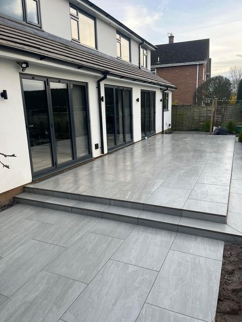 A modern patio while using a traditional look paver. This porcelain paver has realistic characteristics to natural stone. This patio was completed by Dunnington Landscapes Ltd using Aged Kandla Grey porcelain, this paving is available in 600x600mm and 600x900mm. 📞Call our team on 01977 782240 💻Visit the product on our website https://rflandscapeproducts.co.uk/product/aged-kandla-grey-2cm-porcelain-paving/ Details ✔️ Product : Aged Kandla Grey Format - 600x900mm Credit - Dunnington Lands... Patio Paving Ideas Inspiration, Grey Porcelain Paving, Grey Patio Paving, Back Garden Patio Ideas, Grey Patio Ideas, Patio Stones Backyard, Grey Porcelain Patio, Large Patio Ideas, Paving Ideas Outdoor