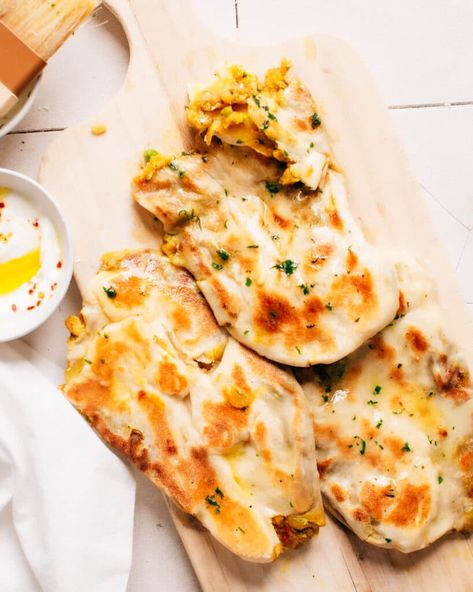 Aloo naan served with dip, one naan torn to reveal filling of potato masala, on a wooden chopping board. Aloo Naan, Naan At Home, Butter Naan Recipe, Easy Naan Recipe, Spiced Potatoes, Butter Naan, Chapati Recipes, Turkish Bread, Indian Flatbread