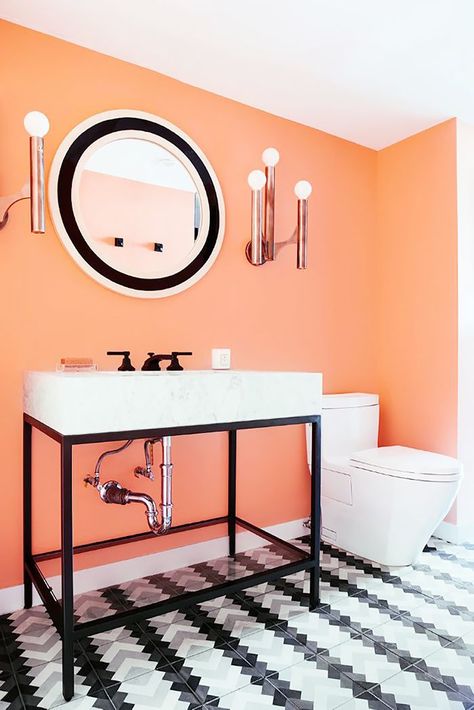 Copper, mid-century style sconces add glamour to this eclectic bathroom with coral walls and black-and-white tiles. Orange Bathrooms Designs, Coral Room, Coral Bathroom, Powder Room Lighting, Bathroom Decor Colors, Orange Bathrooms, Bathroom Color Schemes, Bathroom Color, Trendy Bathroom