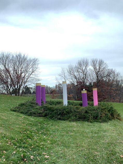 12” diameter sturdy cardboard tubes used for pouring cement forms in building construction were used.The center tube is 7 feet tall and the shortest is 5 feet tall. The tubes come in 12 feet lengths.
The tubes were painted twice using an outdoor semi-gloss latex paint in the 3 advent wreath candle colors.
A 6” gold bling ribbon was applied to each top of the candles using Gorilla Brand outdoor double stick tape strips.
The diameter of this wreath is 16 feet so it can easily be seen from the road Outdoor Advent Wreath, Advent Wreath Lights4fun, Diy Giant Christmas Candles, Advent Candle Display For Church, Large Advent Wreath For Church, Presbyterian Advent Wreath, Wooden Stakes, Giant Christmas Ornaments, Tree Limbs