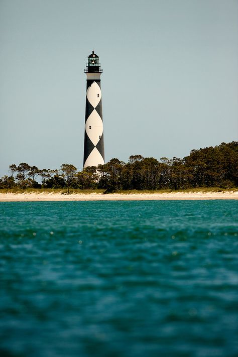 The black-and-white diamond painted Cape Lookout Lighthouse in the Southern Outer Banks of North Carolina is one of the country's most eye-catching lighthouse designs. The black diamonds point in a north-south direction, while the white diamonds point east-west. The checkered daymarker is intended to show direction. The 163-foot high Cape Lookout Lighthouse is one of the few lighthouses that operate during the day. Charlotte NC photographer Patrick Schneider has extensive photo collections of th Cape Lookout Lighthouse, Ocracoke Lighthouse, Oak Island Lighthouse, Nc Lighthouses, Bodie Island Lighthouse, Great American Road Trip, Cape Hatteras Lighthouse, Lighthouse Lighting, Honeymoon Island