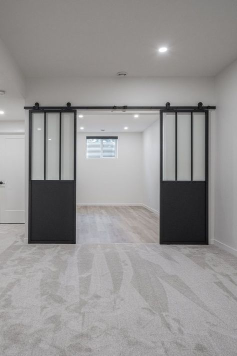 Barn doors were used to create separation between the family room and gym, while also allowing for natural light. Basement Gym And Family Room, Basement Home Gym, Basement Gym, Bedroom Fireplace, Gym Room, Divider Wall, Tile Work, Side Window, Maximize Space