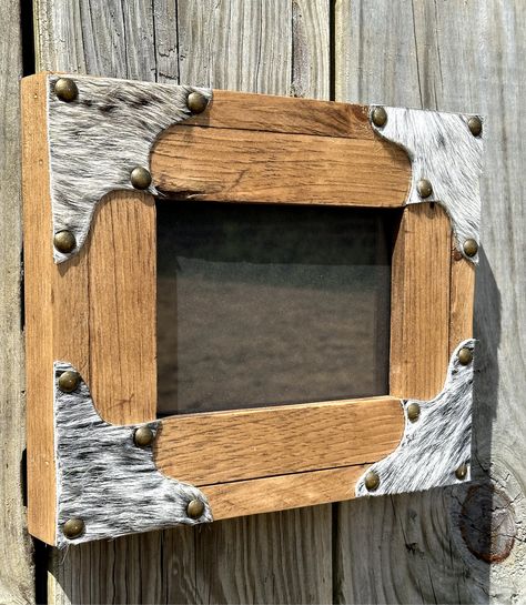 I hand craft these frames from pine wood. They are stained in Early American stain. The corners feature black and white salt & pepper cowhide scallops with antique brass nailhead trim. The colors in the hide may vary from the picture, but will feature the same colors.  These hold an 5x7 picture, overall dimensions are 9 1/2 x 10 1/2. They have a sawtooth hanger for horizontal hanging. They can be hung vertically by the back edge of the frame or can sit on a tabletop. Customization is available as well as bulk order discounts (10 or more). What To Do With Old Frames, Western Wood Projects, Picture Frame Collage Ideas, Cowhide On Wall Ideas, Western Picture Frames, Early American Stain, Cowhide Decor, Building Memories, Wood Working Projects