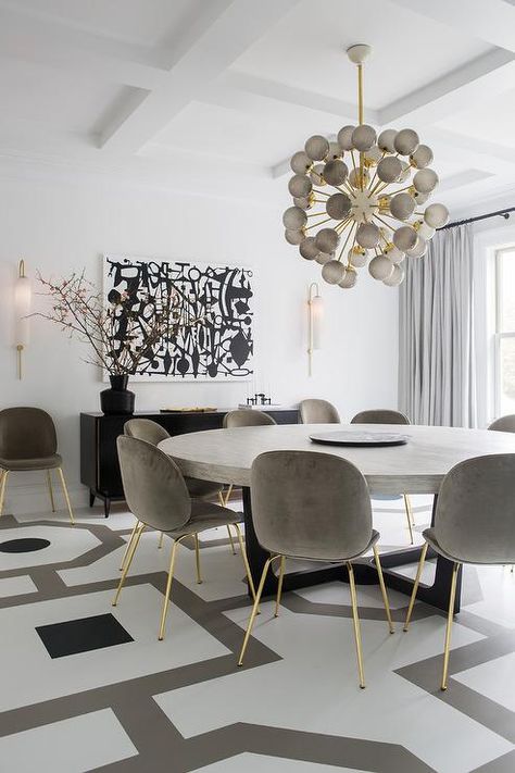 Contemporary white, gray, and black dining room boasts a large, round, gray dining table seating gray velvet dining chairs with gold legs on a white and gray painted wood floor. Round Dining Room Sets, Grey Dining Tables, Round Dining Room Table, Grey Dining Room, Dining Room Contemporary, Round Dining Room, Black Dining, Black Dining Room, Small Kitchens