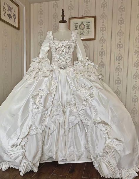 This stunning Luxury Antique Baroque Style Satin Wedding Dress with Floral Long Sleeves is the perfect choice for the bride who wants to make a statement on her special day. This 1800 ball gown features a beautiful baroque-inspired design with intricate details and luxurious satin fabric. The bodice is fitted with a sweetheart neckline, and the long sleeves are adorned with delicate floral appliques. The skirt is full and voluminous, with a sweeping train that adds a dramatic touch. This dress i 1700 Wedding Dress, White Rococo Dress, Wedding Dress Antique, Georgian Wedding Dress, Victorian Era Wedding Dress, Ball Gown Wedding Dress With Sleeves, 17th Century Wedding Dress, 1700s Wedding Dress, Versailles Costumes