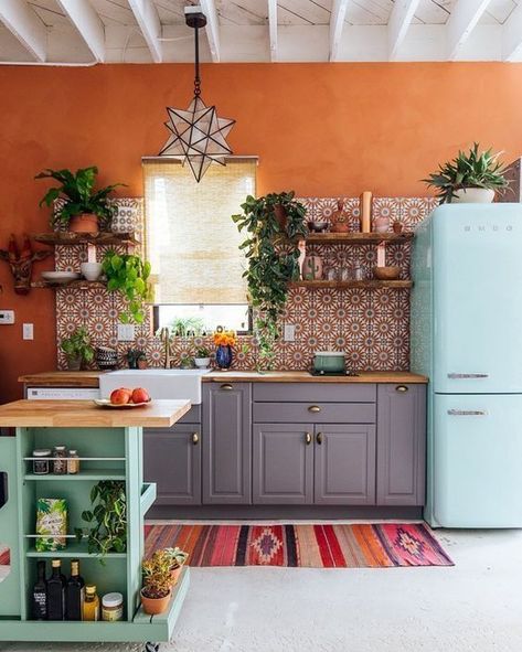 a bright kitchen with orange walls, a bright printed tile backsplash, a blue fridge, a green kitchen island and potted greenery Green Kitchen Island, Boho Kitchen Decor, Bohemian Kitchen, Eclectic Kitchen, Bright Kitchens, Grey Kitchen Cabinets, Boho Kitchen, Interior Modern, Green Kitchen