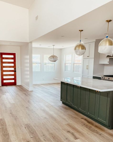 The open kitchen space with kitchen island, breakfast nook, and front door in view Front Door Open To Kitchen, Kitchen Near Front Door, Blue Green Paint Colors, Blue Green Paint, Modern Eclectic Home, Two Tone Cabinets, Blue Green Paints, Raise The Bar, Green Paint Colors