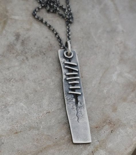 Sterling silver pendant with a torn, melted texture and 7 stitches along the wound.The pendant measures 2 inches long and hangs on a rolo chain.Pictured on a 20" chain.HandmadeSterling silverOxidized finish