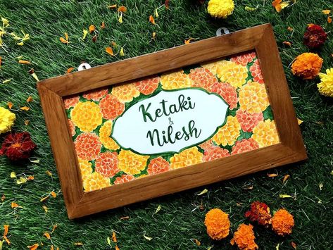 A beautiful hand painted ceramic name plate with a wooden frame. The design and names on the name plate can be customised to make it a unique wedding or house warming gift. It comes with hooks and is easy to hang on the door of your home. #homedecor #newhouse #weddinggift Marigold Name, White Colour Background, Painted Ceramics, Colour Background, Unique Wedding Gifts, Gift For Couples, Wedding Gifts For Couples, Hand Painted Ceramics, Unique Wedding