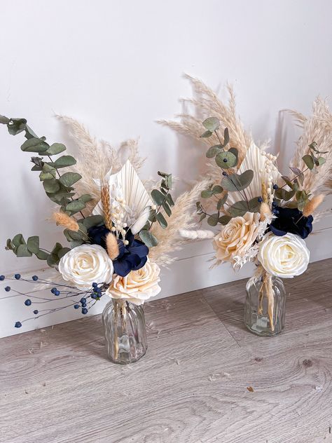 Small vase centrepieces consisting of dried, preserved and artificial flowers. The perfect keepsake from your wedding day and also great gifts for your wedding party! These are totally customisable so if you're looking for a different colour from the main listing (navy blue and sage) please write in the personalisation box 😊 The size of the vase is 14x7.5cm and the total size of the vase and florals is around 40x25cm (sizes may vary). Please note, the price is for one vase centrepiece. For more designs please follow me on Instagram - boho_backdrops Thank you. Kerris x Blue Eucalyptus Wedding Centerpiece, Simple Cheap Centerpieces Wedding, Navy Sage And Cream Wedding, Navy Blue Flower Arrangements Table Settings, Blue Eucalyptus Centerpiece, Rustic Wedding Decor Navy Blue, Wedding Beach Centerpieces, Navy Blue Wedding Centerpieces Diy, Dusty Blue And Sage Green Centerpieces