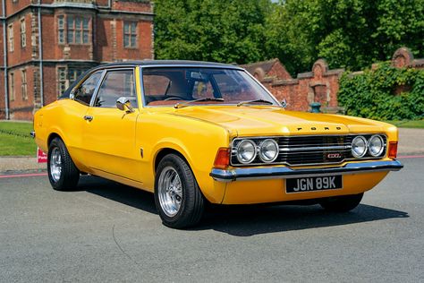 A photograph of a 1971 Ford Cortina MK3. Photographed facing forwards and at an angle the bright yellow, two door car is in the grounds of a stately home with part of the house and walls in the background. Ford Cortina, English Uk, Car Classic, Ford Classic Cars, Coke Bottle, Car Ford, Bottle Design, My Favourite, Classic Cars