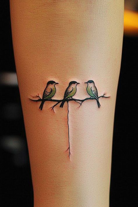 A minimalist tattoo of three birds sitting on a branch on a woman’s arm, ideal for women seeking meaningful and simple ink. Tree Bird Tattoo, Bird Tattoos For Women Arm, 3 Bird Tattoo, Freedom Tattoo Ideas, Small Bird Tattoos For Women, 3 Bird Tattoos For Women, Bird Tattoo Simple, Bird Branch Tattoo, 3 Little Birds Tattoo