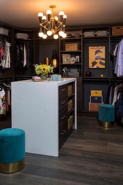 Chic, well styled walk-in closet is illuminated by a black and gold modern chandelier hung over a white quartz waterfall countertop. Black Walk In Closet, Gold Modern Chandelier, Transitional Closet, Honeymoon House, Waterfall Countertop, Island Countertop, Contemporary Closet, Black Closet, Creative Closets