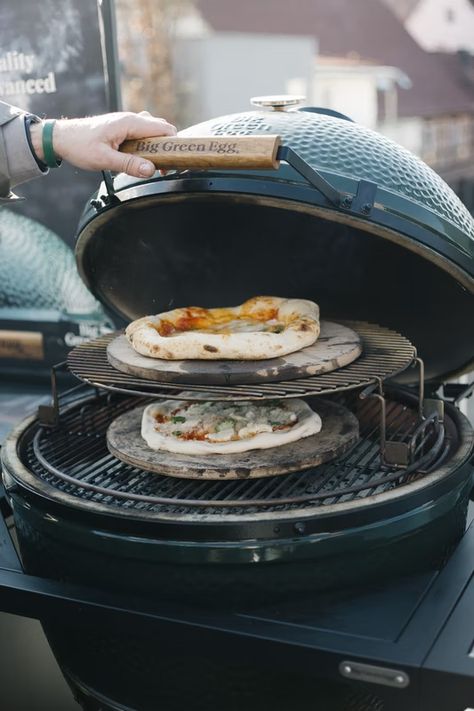 Auf einem grünen Kamadogrill von Big Green Egg werden zwei Pizzen gebacken