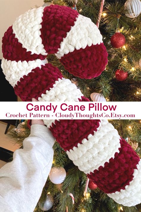 A hand holding an oversized crochet candy cane pillow in front of a Christmas tree. The  pillow is fluffy with burgundy and cream stripes. Candy Cane Pillow, Crochet Candy Cane, Crochet Candy, Crafts Cute, Crocheted Christmas, Winter Crochet, Crochet Decor, Crochet Xmas, Crochet Bedspread