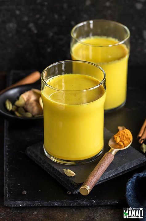 haldi doodh aka golden milk in a glass with another glass in the background and a spoon with turmeric on the side Haldi Milk, Turmeric Milk Benefits, Turmeric Milk Recipe, Haldi Doodh, Milk Photography, Golden Milk Recipe, Indian Food Photography, Turmeric Shots, Milk Benefits