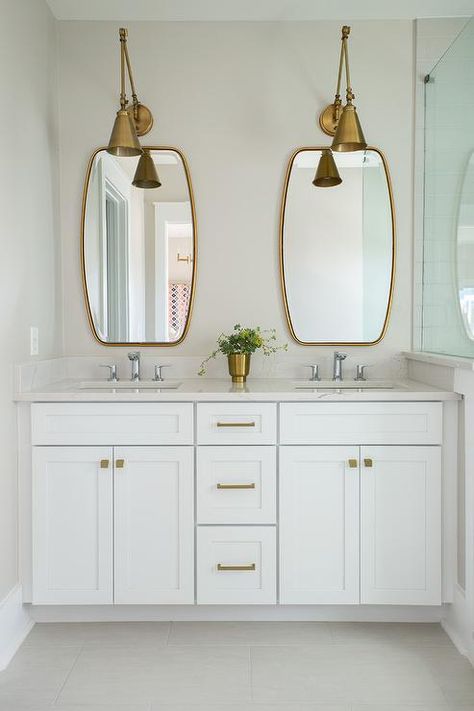 Two antique brass swing-arm pendants illuminate two brass mirrors placed over a white dual washstand adorned with brass hardware topped with white quartz fitted with his and her sinks and polished nickel faucets. Bathroom Lighting Over Mirror, Brass Bathroom Lighting, Polished Nickel Faucet, Small Remodel, Brass Bathroom, Brass Fixtures, Trendy Bathroom, Bathroom Light Fixtures, Bath Room