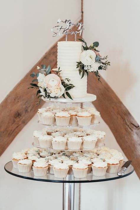 Elegant buttercream 2 tier wedding cake with fresh flowers and surrounded by wedding cupcakes. Wedding in Hampshire at Cain Manor. Two Tiered Wedding Cake With Cupcakes, Single Layer Wedding Cake With Cupcakes, Tall Single Tier Wedding Cake, 2 Tier Wedding Cake With Cupcakes, Cake With Cupcakes Display, 2tier Wedding Cake, Cupcake Tier Cake, Wedding Cake Two Tier, 2 Tier Wedding Cake