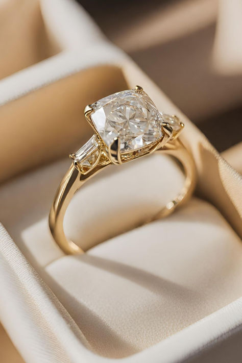 Ranked 10th among our collection of 15 Cushion Cut Diamond Engagement Rings, the Vintage Cushion Cut Diamond Ring with Baguette Side Stones in Yellow Gold showcases a harmonious blend of classic charm and modern sophistication. Click below to discover more captivating designs. Square Engagement Rings With Band Cushion Cut, Engagement Rings Design Gold, Cushion Engagement Ring Vintage, Wedding Rings Cushion Cut Gold Band, Gold Engagement Ring With Side Stones, Bevel Setting Engagement Ring, Trilogy Engagement Ring Cushion Cut, Cushion Cut Engagement Ring With Thick Band, Vintage Proposal Ring