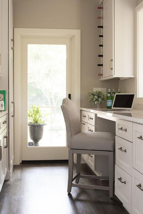 Well organized white and gray kitchen pantry features a light gray linen camelback counter stool placed at a built-in desk fitted with white shaker drawers adorned with satin nickel pulls and a calcutta quartz desk top. Walking Pantry, Pantry Desk, Counter Height Desk, White And Gray Kitchen, Cozy Transitional, White Built Ins, Kitchen Desks, Kitchen Pantry Cabinets, Gray Kitchen