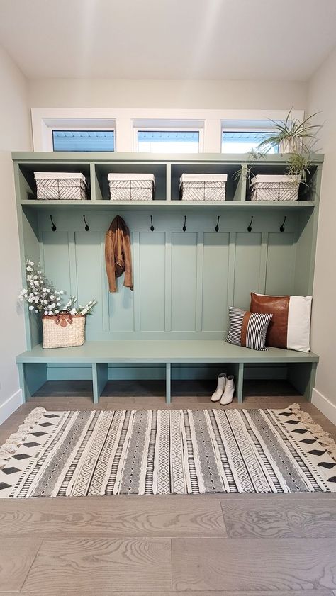 Mudroom cubbies and storage in a light greenish blue color with white and black wire storage baskets, brown leather and white cotton accent pillows, rattan bag with flowers, brown leather jacket and white boots. Hampton Style Home, Refresh Home, Mudroom Cubbies, Functional Mudroom, Mudroom Remodel, Mudroom Makeover, White Tile Backsplash, Mudroom Decor, Mud Rooms