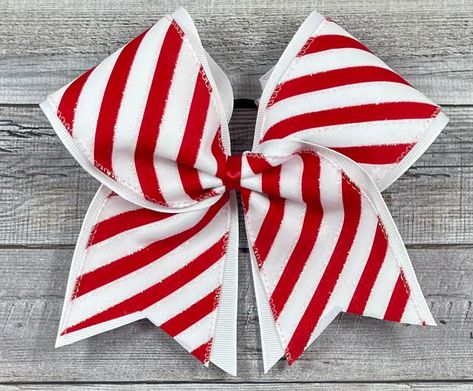 "This listing is for one Christmas Cheer Bow in a red and white Christmas stripe design. Made with 3\" wide grosgrain ribbon, heat transfer vinyl, and black hair band. Ribbon is heat sealed to prevent fraying. Bow measures 7\" wide by 7\" long.  It is a 'standard' cheer bow size. Team orders/Custom orders are available upon request. Please message requests!" Holiday Cheer Bows, Sparkly Cheer Bows, Christmas Cheer Bows, Black Hair Band, Competition Bows, Christmas Stripes, Glitter Cheer Bow, Red And White Christmas, Bow Tutorial