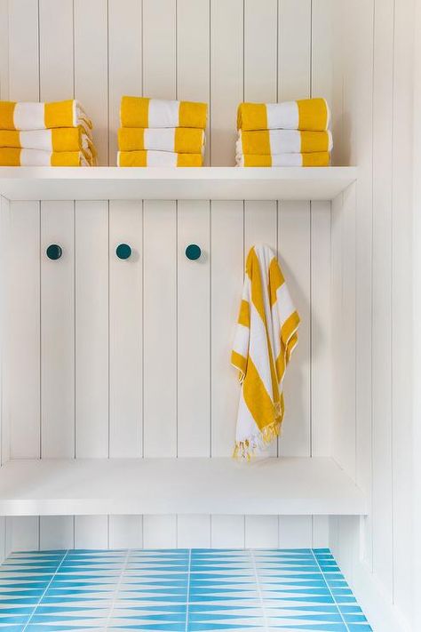 White and blue turquoise tiles lead to a white built-in bench fixed against vertical shiplap trim beneath peacock blue towel hooks. Chevron Floor Tile, Shiplap Trim, Pool House Cabana, Pool House Bathroom, Art Curation, Turquoise Tile, Herringbone Wallpaper, Custom Millwork, Pool Bathroom