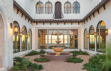 this spanish styled home has the most gorgeous courtyard with windows that overlook the lake it sits on. #homes #interiordesign #architecture #archdaily #archdigest #customdesign #design #archdesign #custombuild Courtyard With Arches, Spanish Modern Courtyard, Spanish Style Carport, Spanish Style Homes With Courtyard, Courtyard Spanish Style, Spanish Hacienda Courtyard, Modern Spanish Staircase, Modern Spanish Courtyard, Spanish Windows Exterior