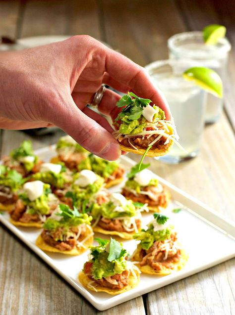 Chicken tostadas are a festive and delicious party food especially when they're bite size! Five layers of flavor piled on to a round tortilla chip (instead of traditional tostada shells). This version has refried beans, tender chicken with Mexican spices, cheese, guacamole, sour cream and fresh cilantro. But it's entirely versatile, swap in any ingredients you like! Mexican Appetizer Recipes, Mexican Finger Foods, Mini Antipasti, Mexican Refried Beans, Mexican Appetizer, Mexican Dinner Party, Mexican Party Food, Chicken Tostadas, Mexican Appetizers